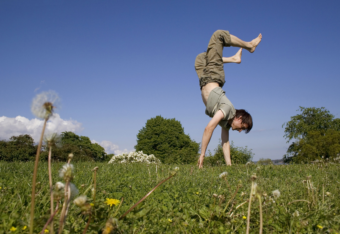 A young man is doing a handstand on the grass.